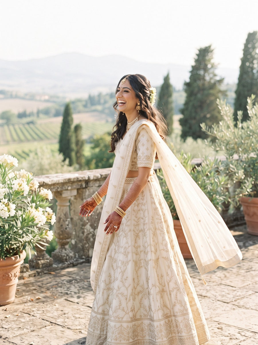 A bride in an ivory and gold lehenga on a sunlit Italian terrace